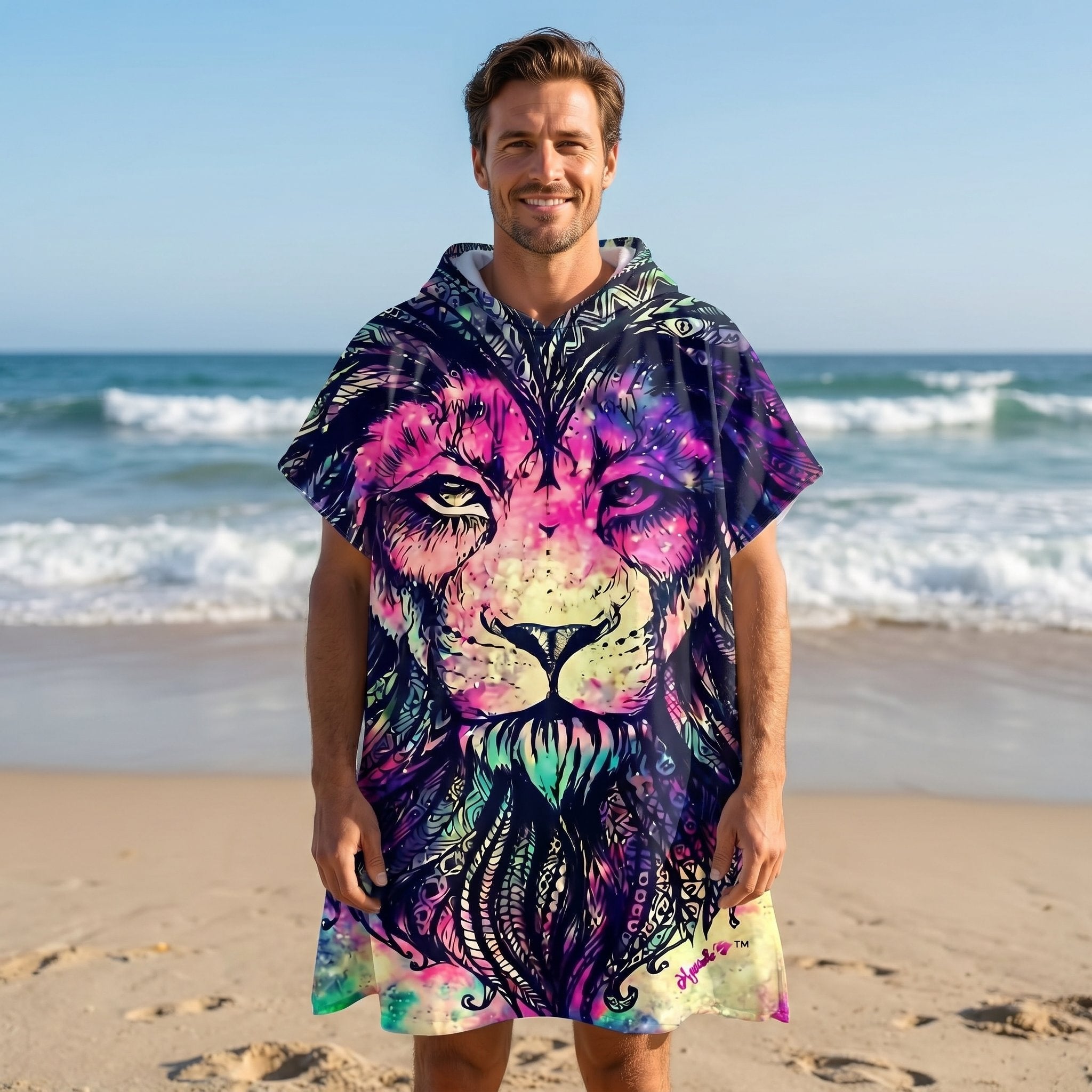 Poncho serviette à capuche motif lion psychédélique, porté par un homme debout face à la mer.