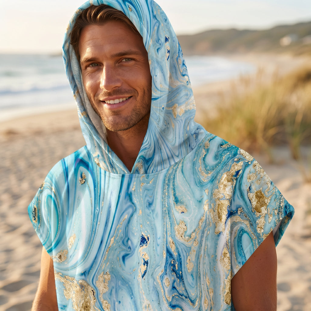 Poncho serviette à capuche motif marbre écume dorée, porté par un homme souriant, cadrage serré sur le buste et le visage.