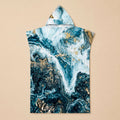 Poncho serviette à capuche motif marbré bleu et or, présenté à plat sur un fond uni clair.