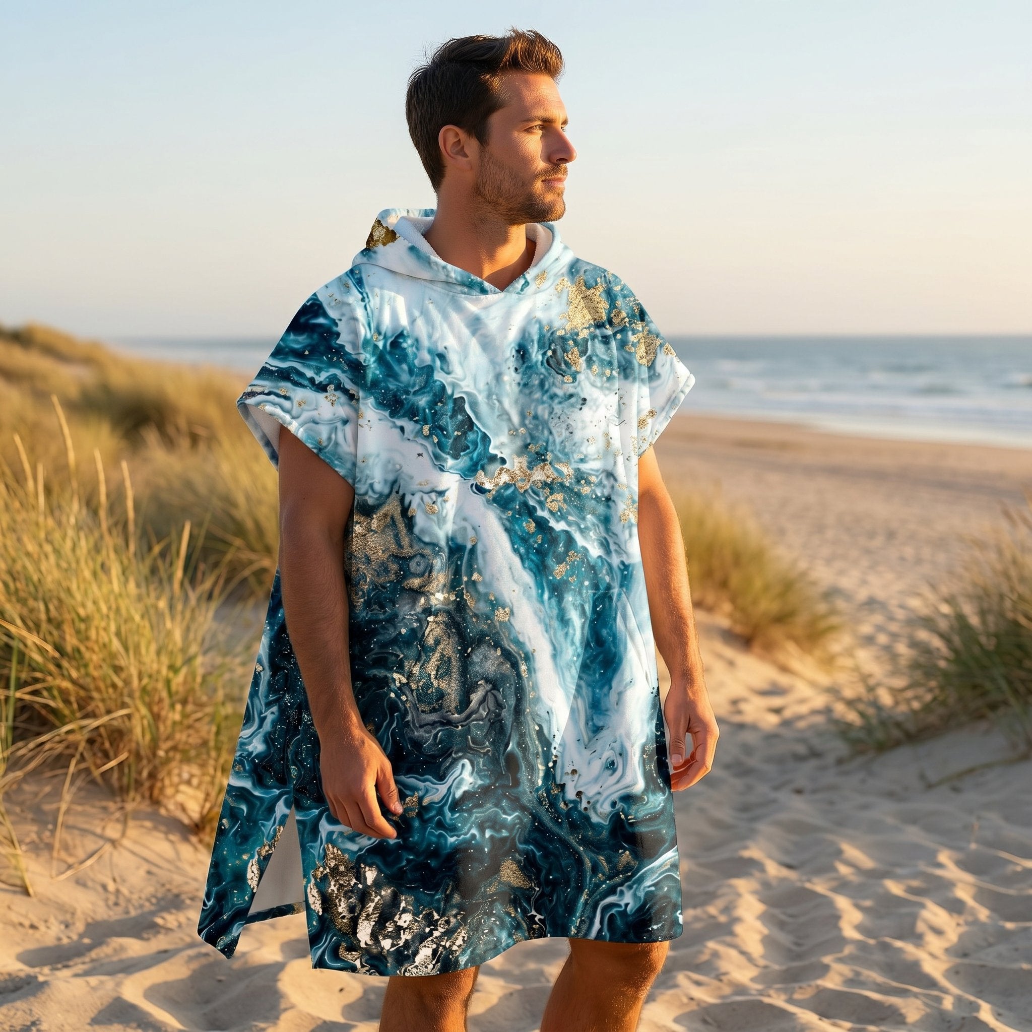Poncho serviette à capuche motif marbré bleu et or, porté par un homme de profil sur la plage.
