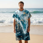 Poncho serviette à capuche motif marbré bleu et or, porté par un homme debout face à l'océan.