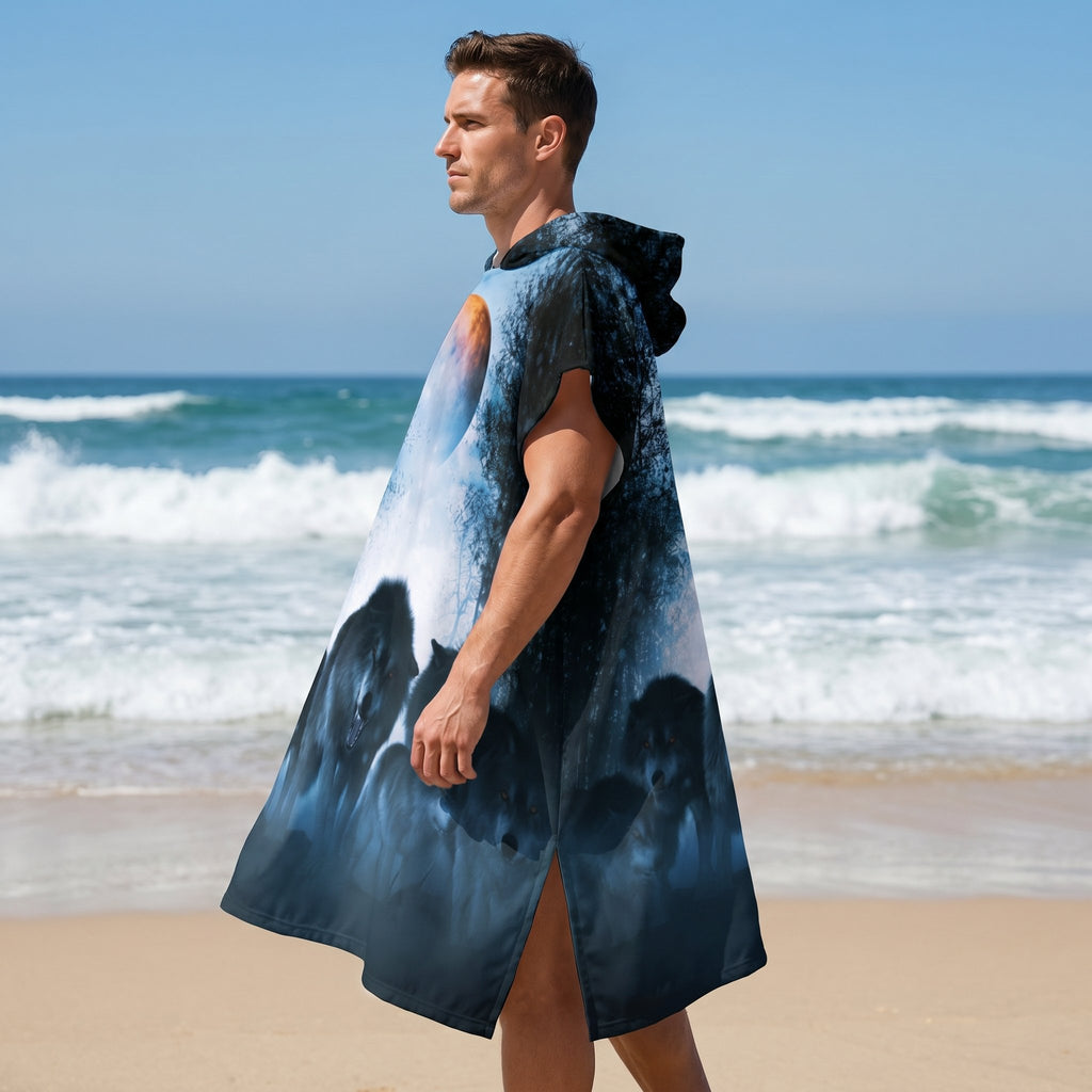 Poncho serviette a capuche motif meute de loups, porté par un homme de profil sur la plage, regardant vers la mer.