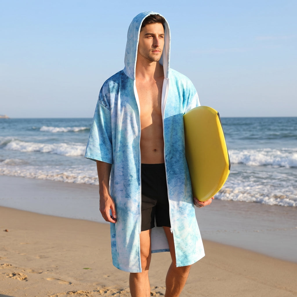 Poncho serviette à capuche motif requin-baleine, porté par un homme sur la plage, tenant une planche de bodyboard.