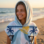 Poncho serviette à capuche motif requin hawaïen, porté par une femme souriante, la capuche sur la tête, en gros plan.
