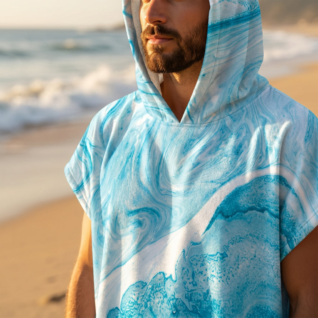 Poncho serviette a capuche motif vague marbree bleue, gros plan sur le buste et la capuche, en exterieur.