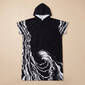 Poncho serviette a capuche motif vague noir et blanc, présenté à plat sur un fond beige uni.