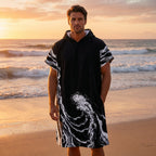 Poncho serviette a capuche motif vague noir et blanc, porté par un homme de face sur la plage.