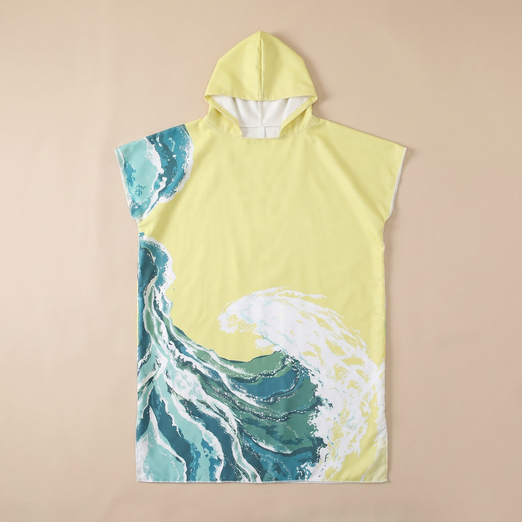 Poncho serviette à capuche motif vagues jaune pâle, posé à plat sur un fond beige uni.