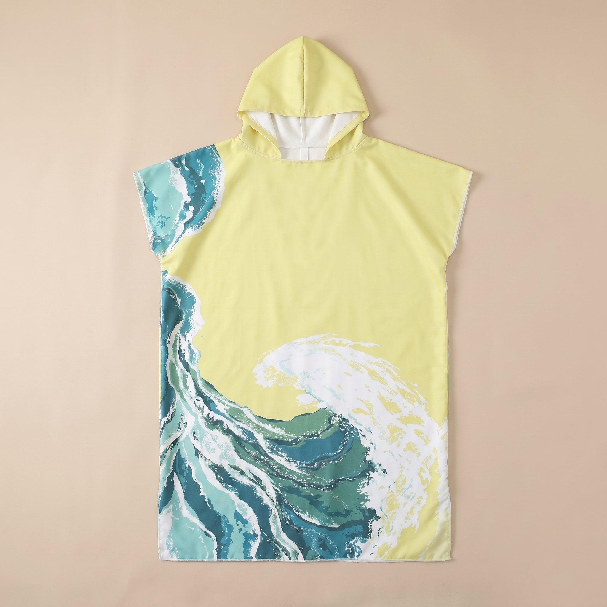 Poncho serviette à capuche motif vagues jaune pâle, posé à plat sur un fond beige uni.