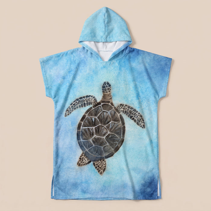 Poncho serviette à capuche motif tortue marine, posé à plat sur un fond uni clair.