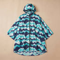 Poncho de pluie à capuche motif chevrons turquoise, posé à plat sur un fond uni beige.