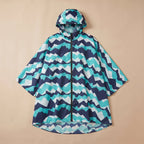Poncho de pluie à capuche motif chevrons turquoise, posé à plat sur un fond uni beige.