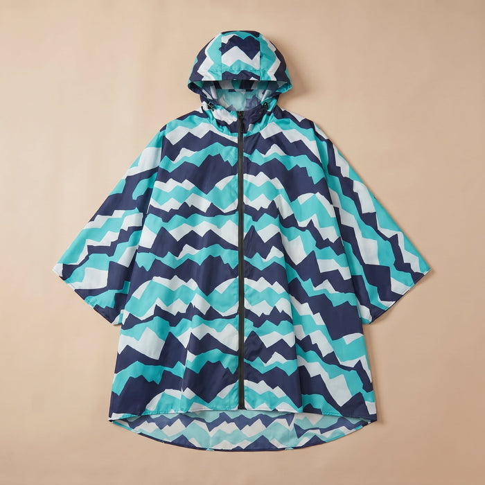 Poncho de pluie à capuche motif chevrons turquoise, posé à plat sur un fond uni beige.