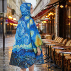 Poncho de pluie à capuche motif Ciel étoilé, porté par une femme de profil, devant une terrasse de café.
