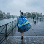 Poncho de pluie à capuche motif Ciel étoilé, porté par une femme de dos, sur un pont en bois sous la pluie.
