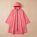Poncho de pluie à capuche corail uni, posé à plat sur un fond clair et uni.