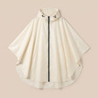 Poncho de pluie à capuche crème uni, présenté à plat sur un fond beige clair, vue de face.