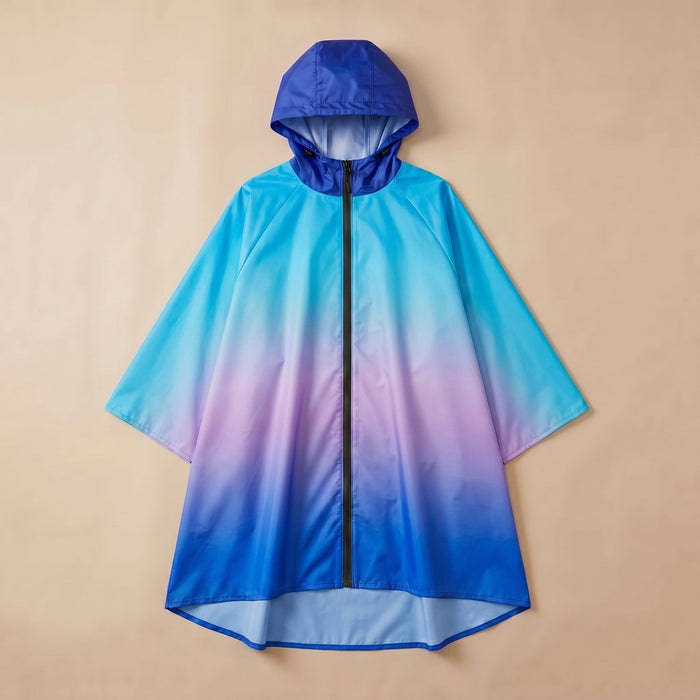 Poncho de pluie à capuche dégradé bleu et violet, posé à plat sur un fond uni beige.