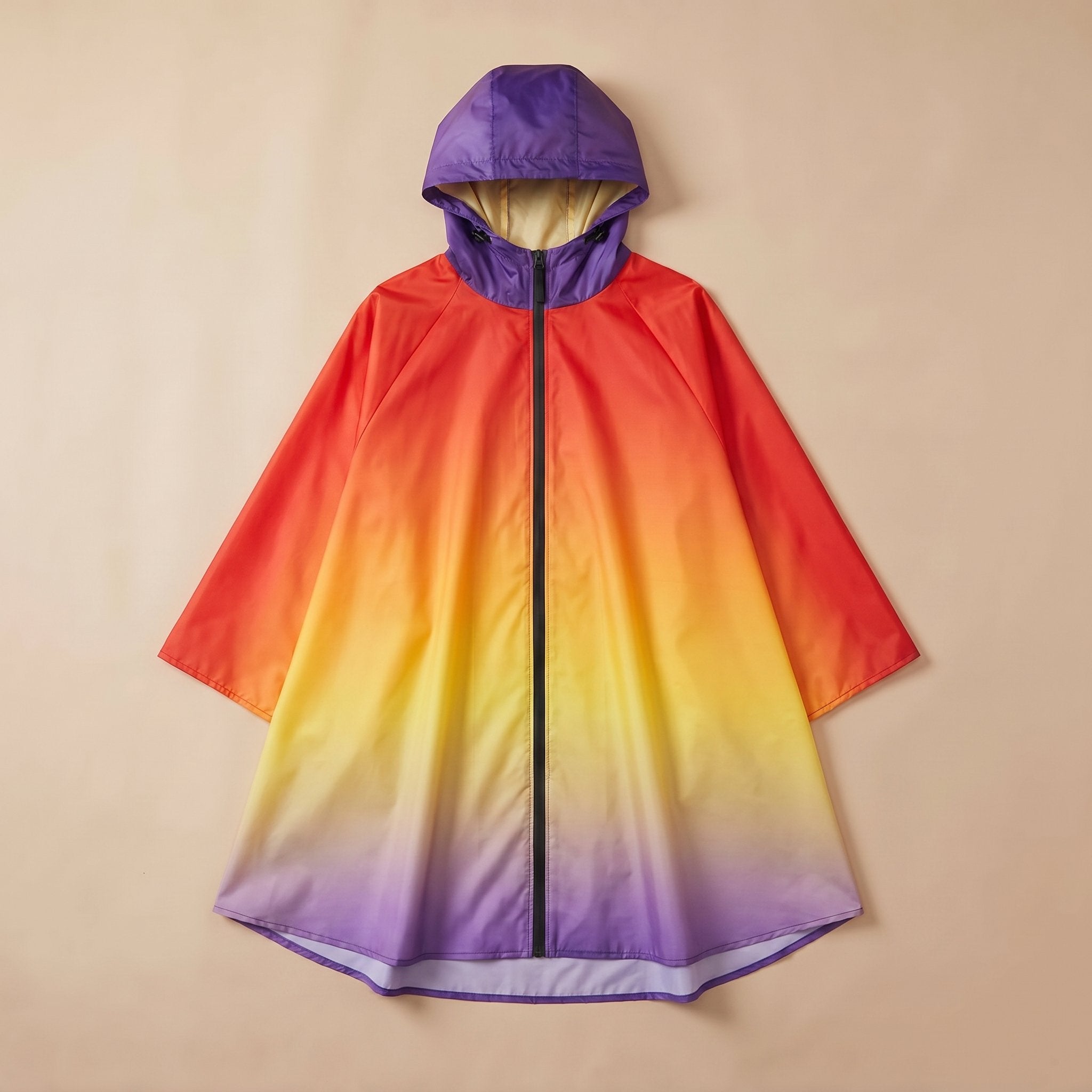 Poncho de pluie à capuche dégradé feu, posé à plat sur un fond uni beige clair.