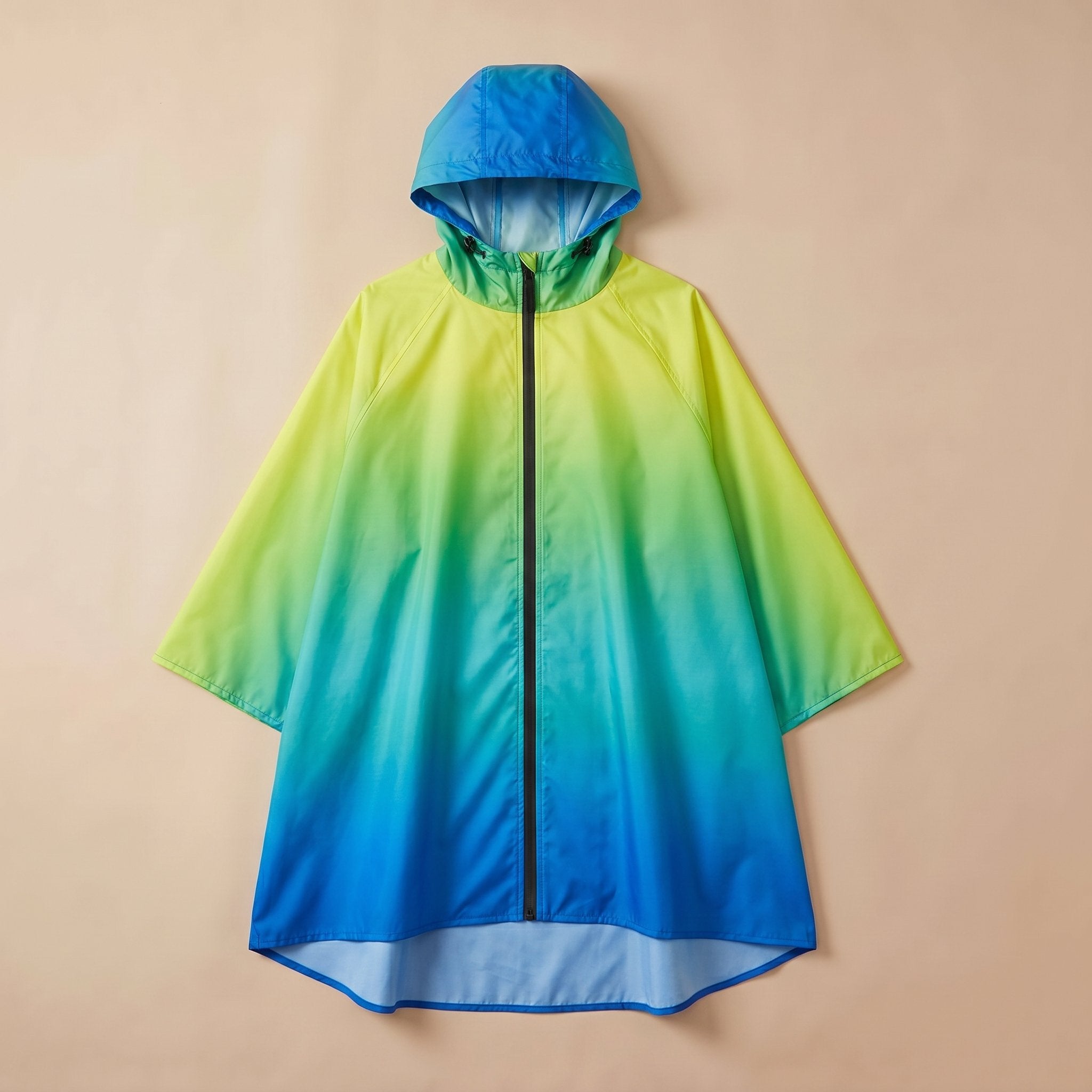 Poncho de pluie à capuche dégradé lagon, posé à plat sur un fond uni beige clair.