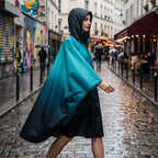 Poncho de pluie à capuche dégradé turquoise et nuit, porté par une femme marchant de profil dans une ruelle.