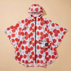Poncho de pluie à capuche femme à fleurs posé à plat, motif floral rouge et blanc, avec sa pochette de rangement assortie