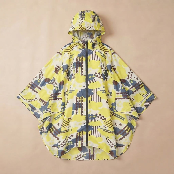 Poncho de pluie à capuche motif graphique jaune, posé à plat sur un fond uni beige.