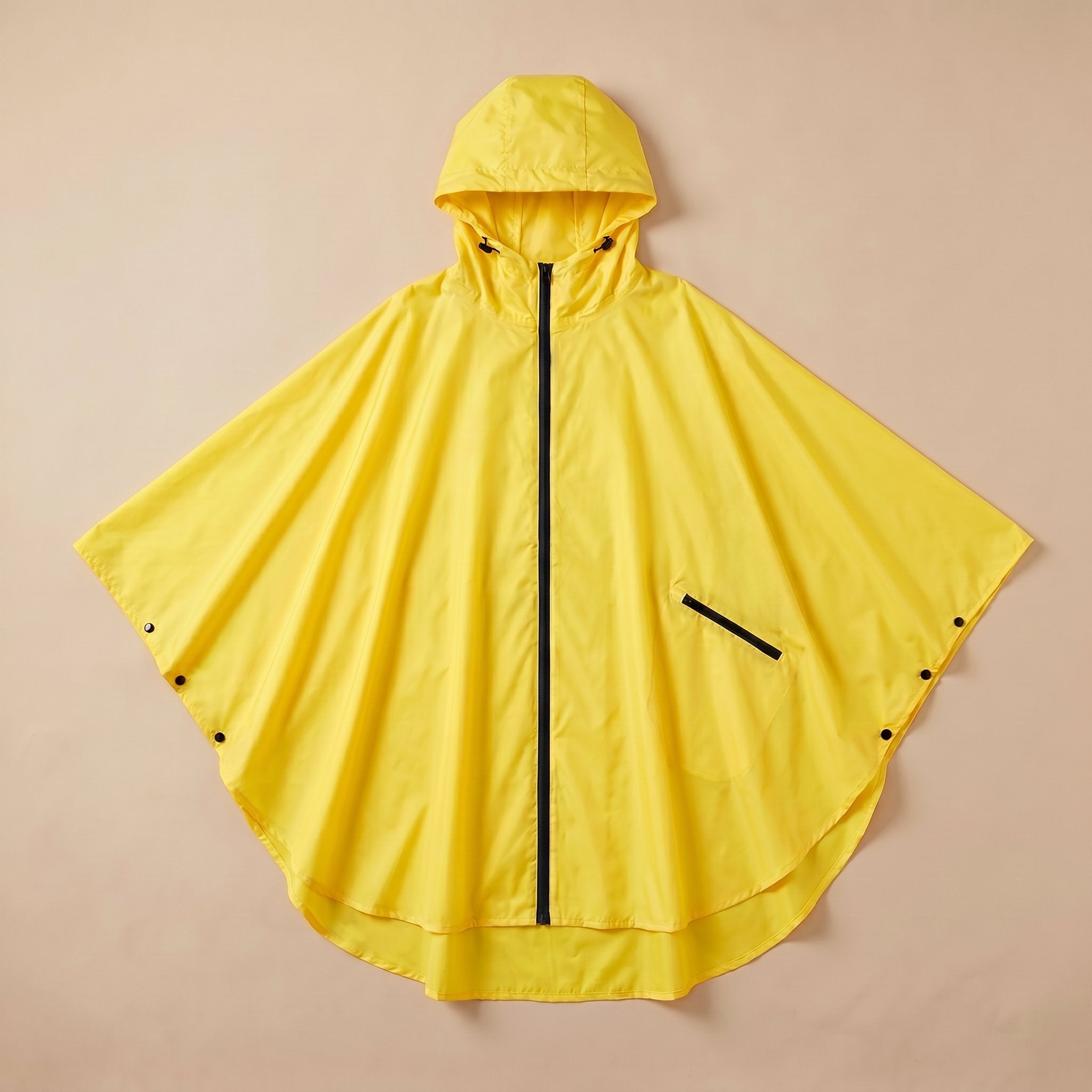 Poncho de pluie à capuche jaune uni, présenté à plat sur un fond clair, vue de dessus.