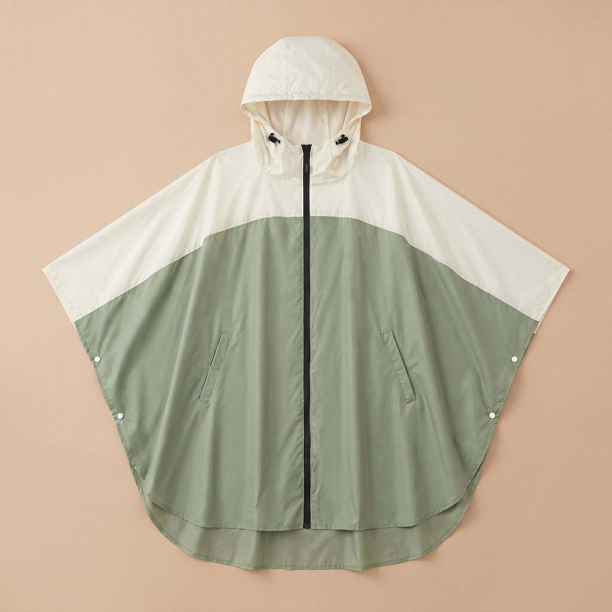 Poncho de pluie à capuche kaki et crème, présenté à plat sur un fond uni.