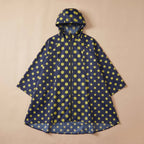 Poncho de pluie à capuche motif Pois jaunes, posé à plat sur un fond uni et clair.