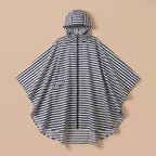 Poncho de pluie à capuche rayures marines, posé à plat sur un fond uni beige, vue de face.