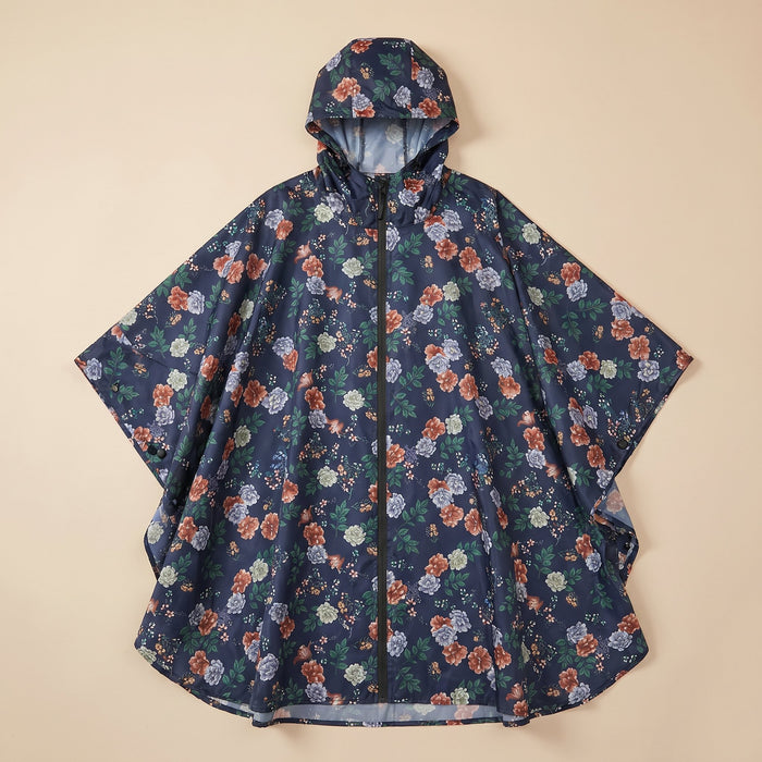Poncho de pluie à capuche motif roses marine, posé à plat sur un fond uni beige.