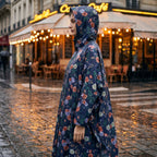 Poncho de pluie à capuche motif roses marine, porté par une femme de profil, capuche relevée.