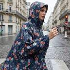 Poncho de pluie à capuche motif roses marine, porté par une femme en gros plan, capuche sur la tête.