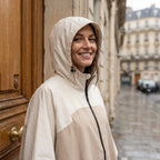 Poncho de pluie à capuche sable uni, porté par une femme souriante en gros plan avec la capuche.
