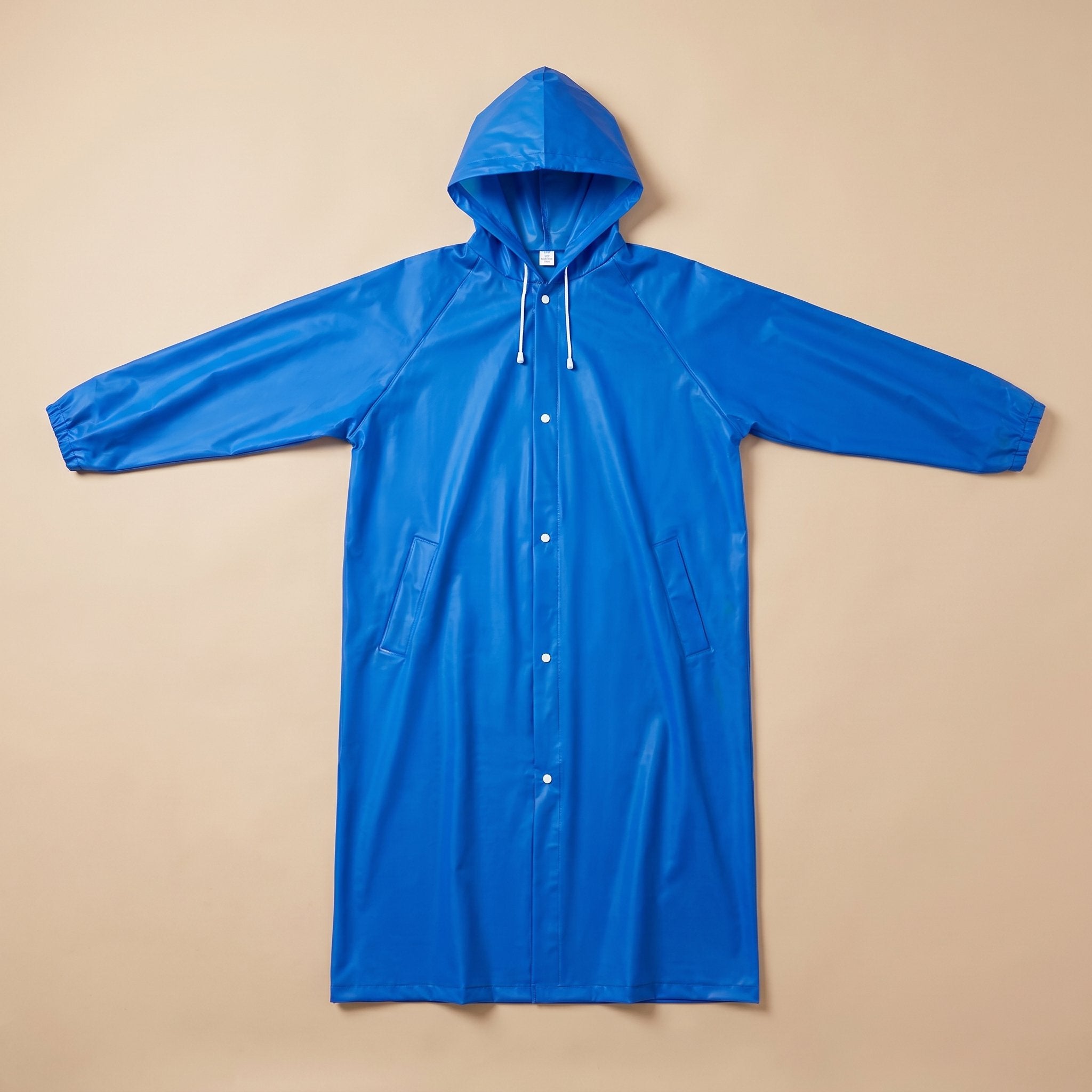 Poncho de pluie long bleu roi, présenté à plat sur un fond uni, vue de face.