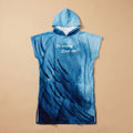 Poncho serviette à capuche motif baleine et lune, posé à plat sur un fond uni beige.