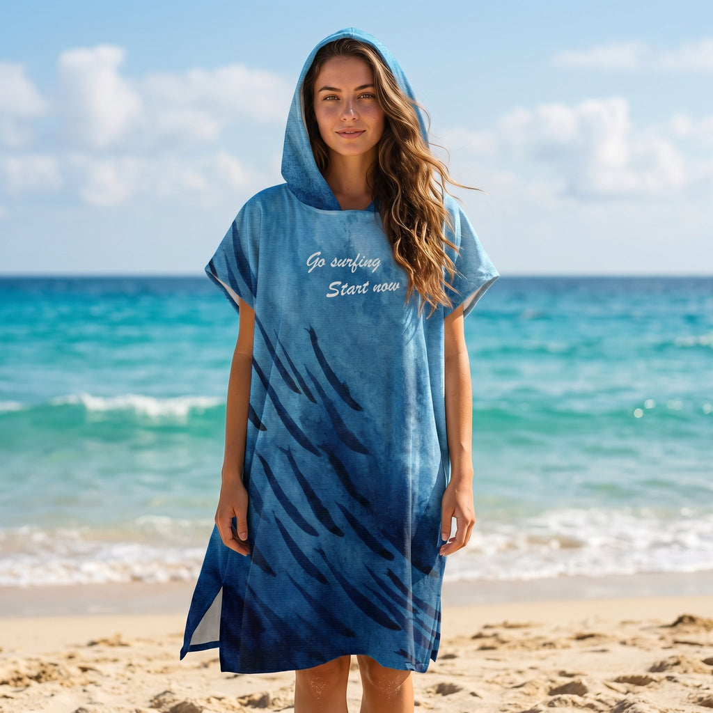 Poncho serviette à capuche motif baleine et lune, porté par une femme de face sur une plage, cadrée à mi-corps.
