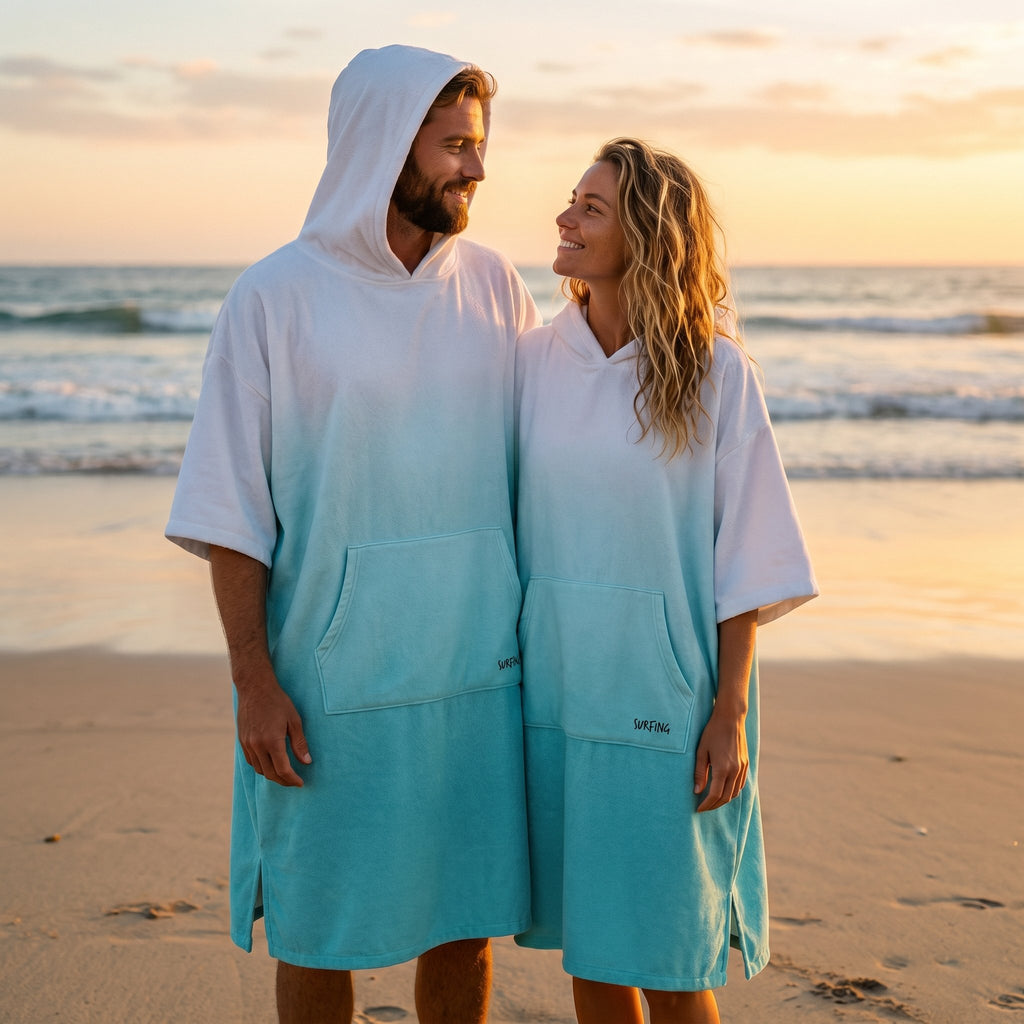 Poncho serviette à capuche dégradé menthe, porté par un couple souriant se faisant face sur la plage.