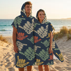 Poncho serviette à capuche motif shakas colorés, porté par un homme et une femme de profil sur le sable.
