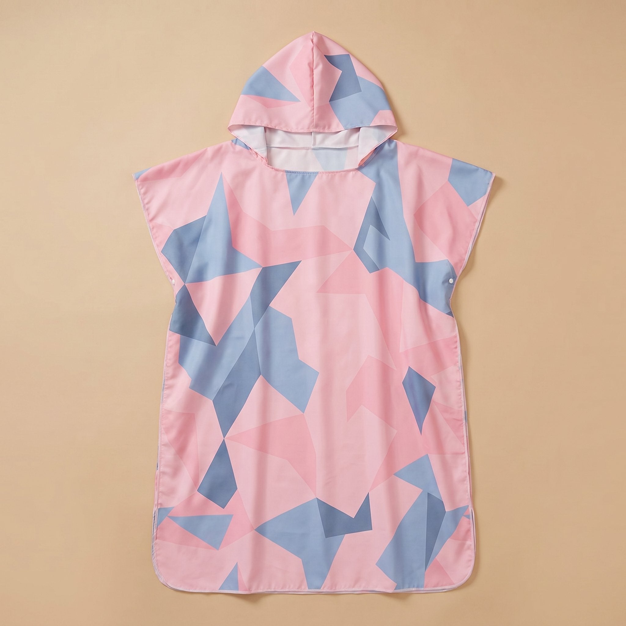 Poncho de surf à capuche · Triangles, motif géométrique rose et bleu clair, présenté à plat sur un fond uni beige.