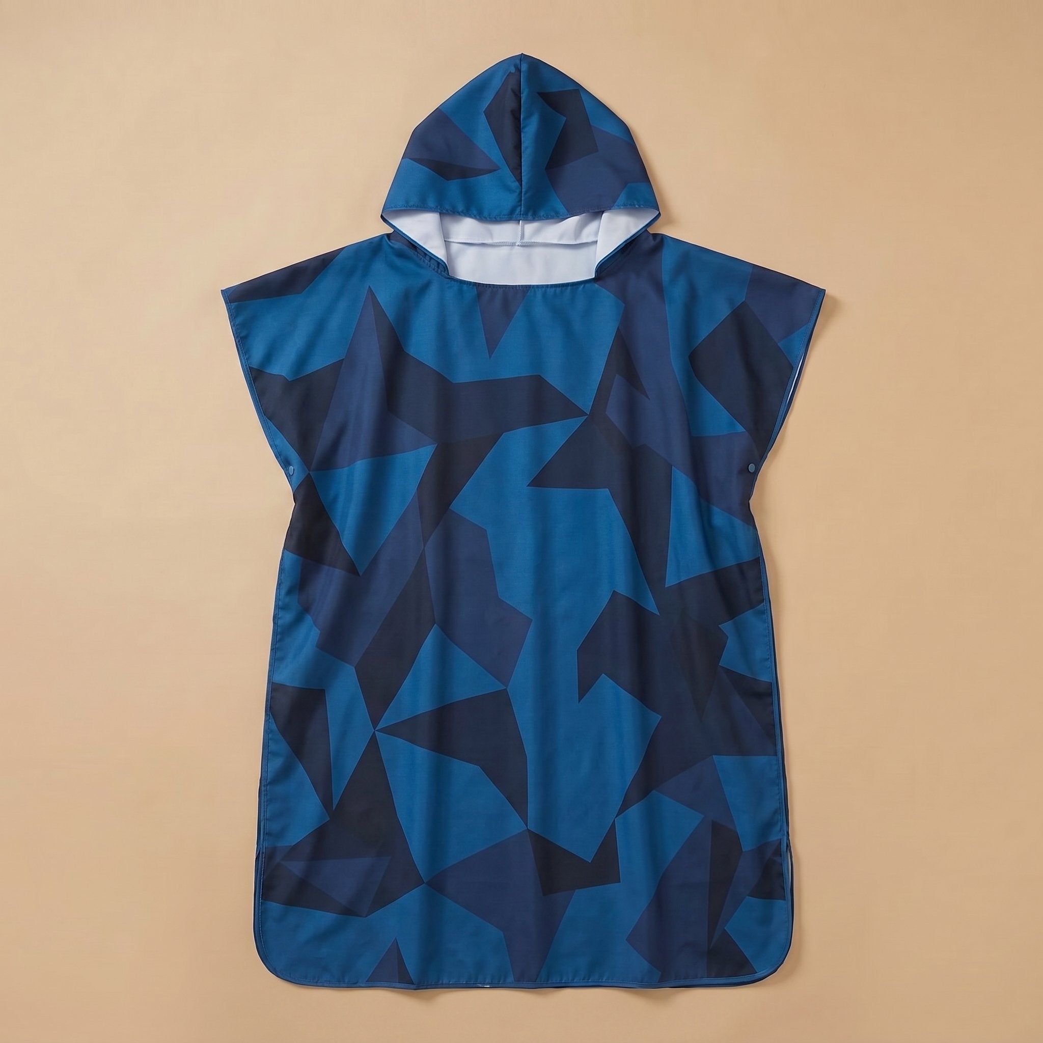 Poncho de surf à capuche · Triangles, motif géométrique bleu foncé et noir, présenté à plat sur un fond uni beige.