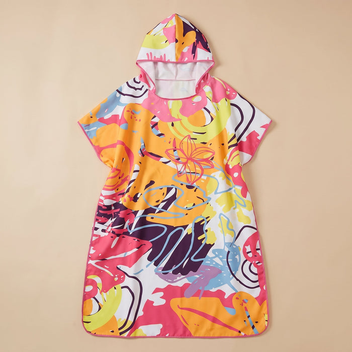 Poncho serviette a capuche motif tropical rose et jaune, posé à plat sur un fond beige clair.