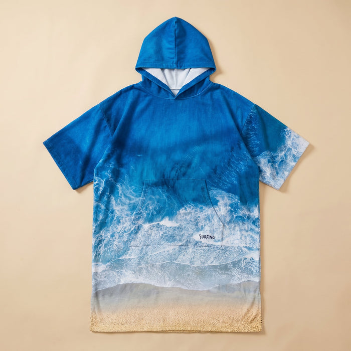 Poncho serviette à capuche motif vague océan, présenté à plat sur un fond beige clair.