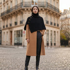 Poncho en laine femme noir, porté par une femme debout de face au milieu d'une place urbaine.