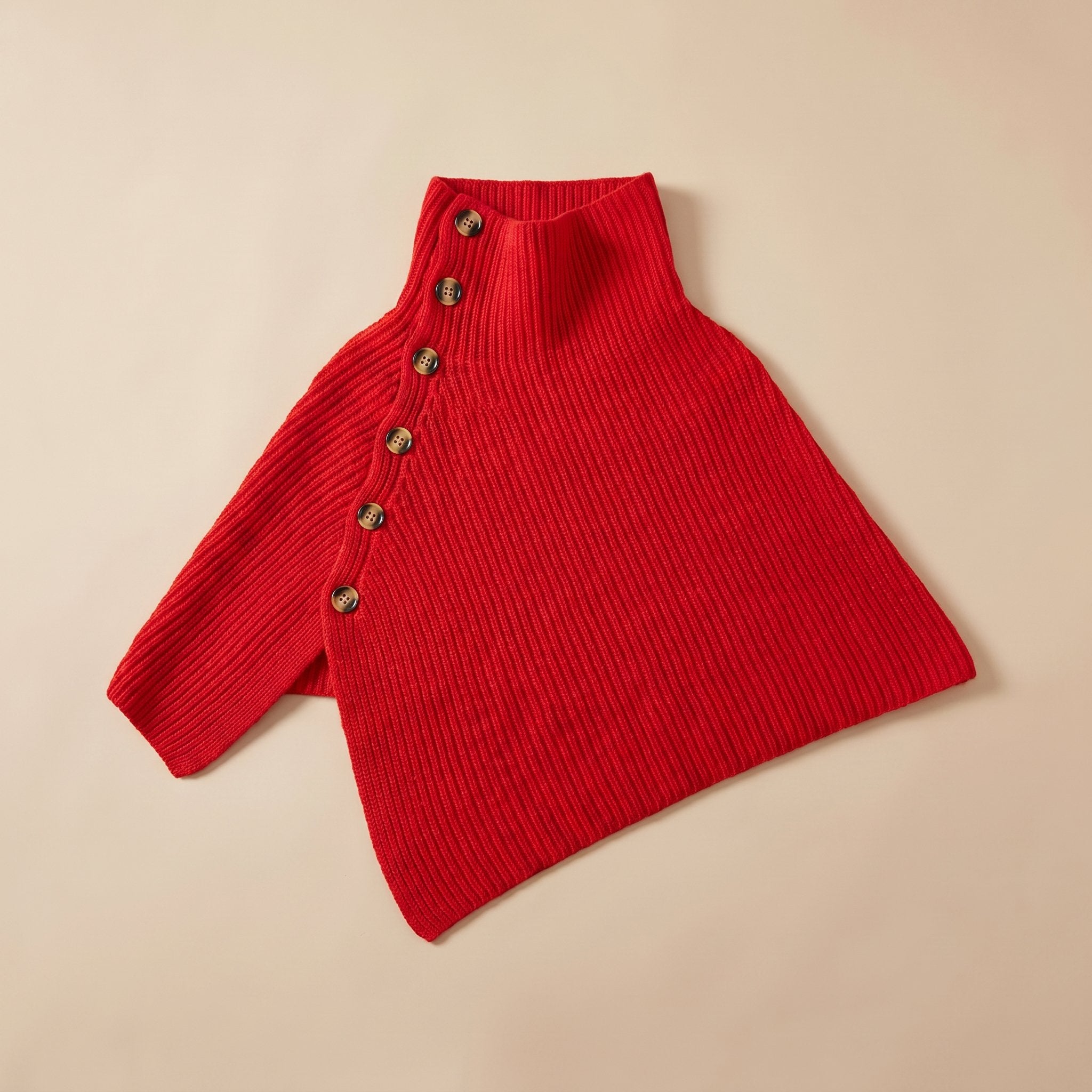 Poncho en laine femme rouge, avec col montant et boutons, présenté à plat sur un fond neutre.