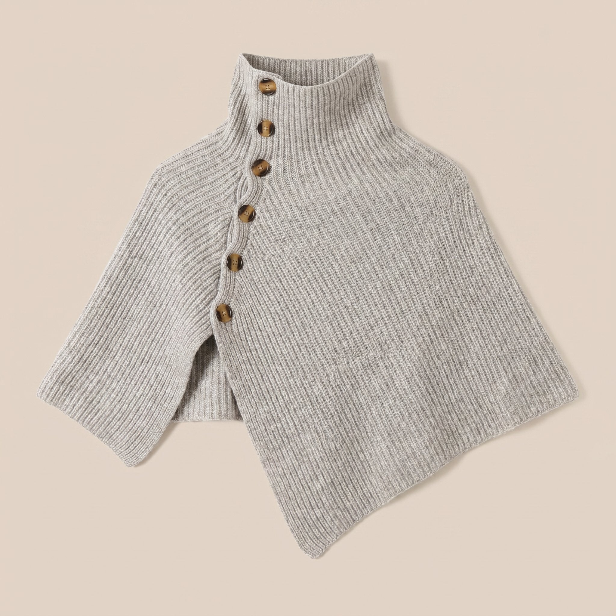 Poncho en laine femme gris, avec col montant et boutons, posé à plat sur un fond uni et doux.
