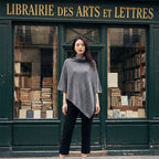 Poncho en laine femme col roulé gris porté par une femme, devant une librairie ancienne.