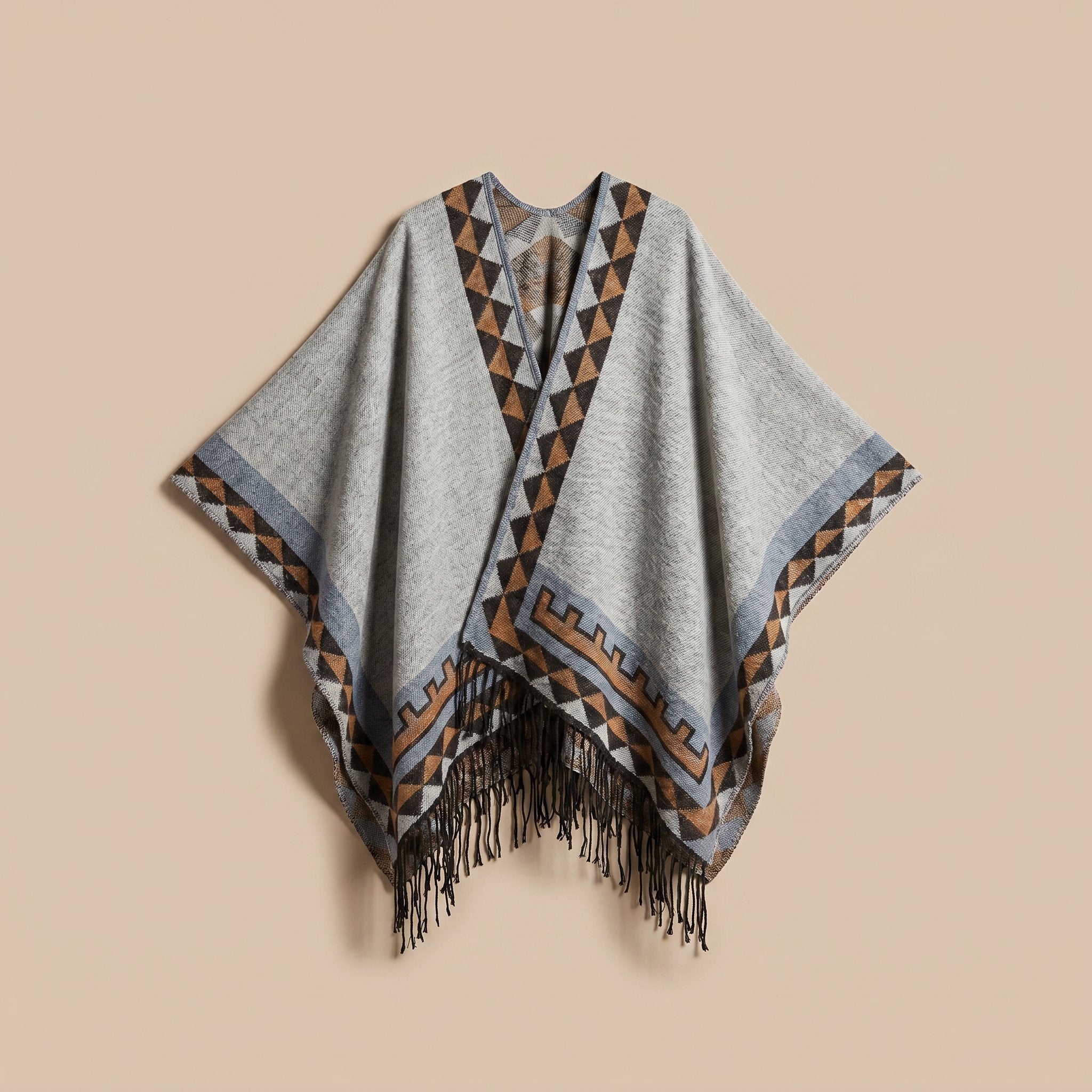 Poncho femme chaud à motif aztèque et franges gris clair, avec motifs géométriques marron et bleus, posé à plat