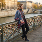 Poncho femme chaud à motif aztèque et franges bleu, porté par une femme de profil appuyée sur un pont avec des cadenas